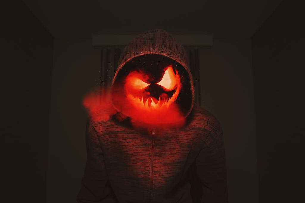 A spooky pumpkin head in a hoodie exudes a creepy Halloween vibe with red smoke.